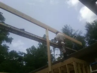 Carpenter setting a ridge beam over a new addition frame — Ice Dam Removal by Roofing Brothers in Cullen