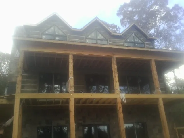 Dormers and porch framing on a large log home under construction — Roof Coating work by our crew in Cullen