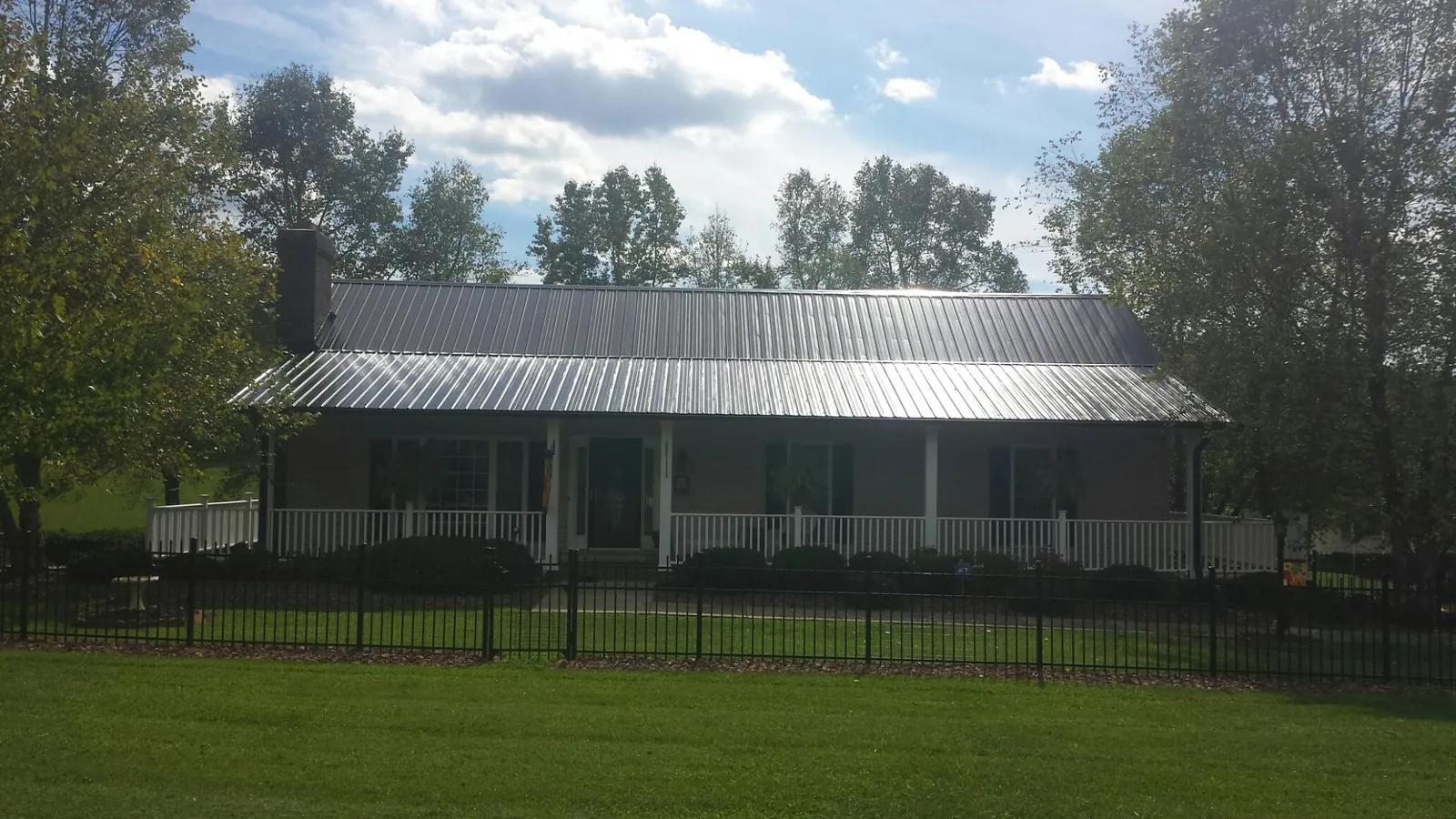 Gray metal roof on a brick ranch with a full width front porch — Gutter Guard Installation work by our crew in Cullen